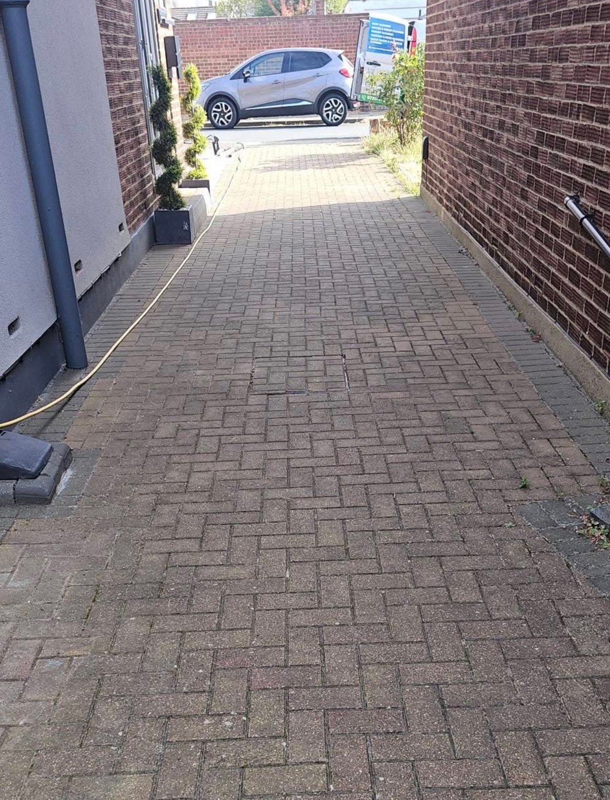 Brick paved driveway with blue car before pressure washing