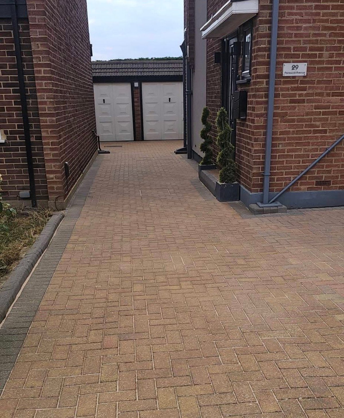Brick paved driveway leading to double garage doors after professional cleaning