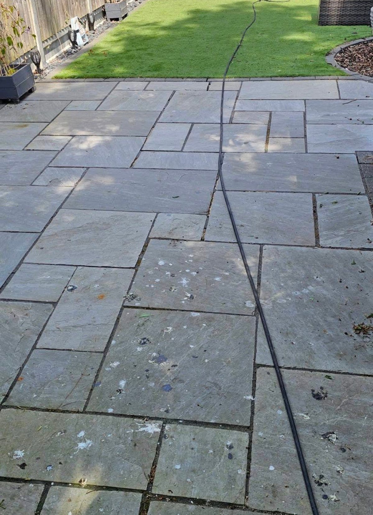 Cracked concrete patio with large fissure running through stone pavers before restoration